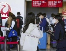 Una trabajadora de la aerolínea Japan Airlines ayuda a viajeros en el Aeropuerto Internacional de Osaka, luego de que la compañía anunció que había sufrido un ciberataque. AP