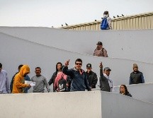 Migrantes deportados saludan en el puerto fronterizo de El Chaparral, este miercoles en Tijuana; mismos que ya permanecían en centros de detención desde la administración del ahora expresidente Joe Biden. EFE/ J. Terríquez