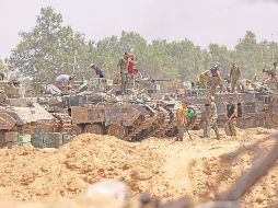Soldados israelíes trabajan en sus vehículos blindados cerca de la frontera con Gaza. El Ejército anunció la expansión de su ofensiva para liberar rehenes y derrotar a Hamás. AFP