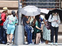 Capitalinos recurren a sombrillas y a las fuentes para mitigar el calor en Alameda Central. SUN/B. Fregoso.