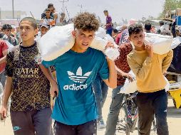 Gazatíes cargan costales de grano, con el temor de que el conflicto entre Israel e Irán haga que la comunidad internacional los olvide. AFP