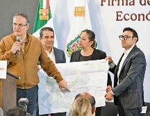 Marcelo Ebrard señala un plano con la distribución que tendrá el clúster en Puebla, que también impulsará la vivienda en la zona. ESPECIAL