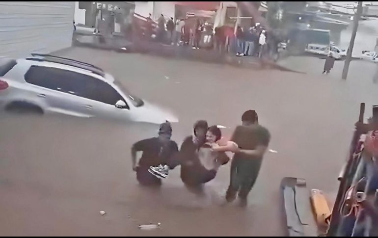 Locatarios y clientes del Mercado de Abastos brindaron apoyo a una joven que se quedó atascada dentro de su vehículo, varado en medio de la inundación. ESPECIAL