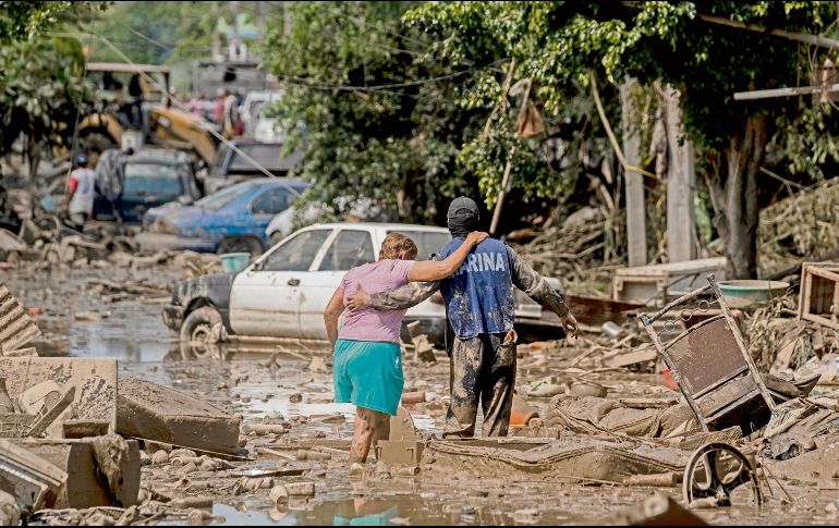 Un elemento de la Marina de México ayuda a una mujer a cruzar una calle inundada en Poza Rica, Veracruz. AP