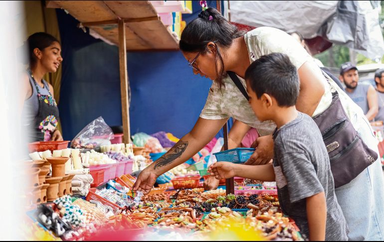 Una mujer y su hijo adquieren artículos para su altar de Día de Muertos, tradición que impulsa la economía local. EL INFORMADOR