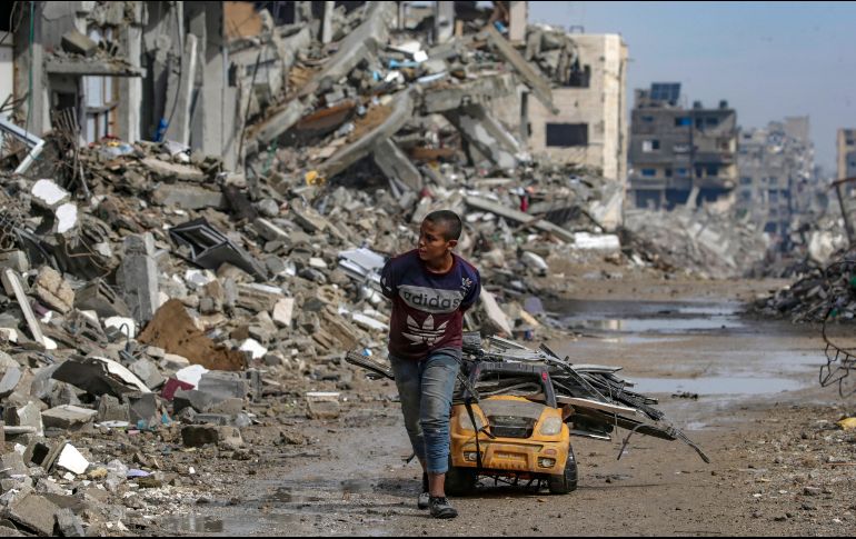 Un niño acarrea metales para reciclar sobre un carro de juguete, con los primeros charcos de lluvia como amenaza. EFE/M. Saber