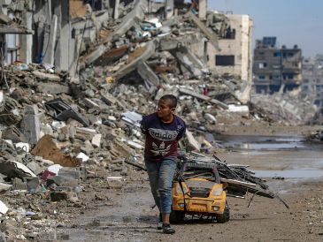 Un niño acarrea metales para reciclar sobre un carro de juguete, con los primeros charcos de lluvia como amenaza. EFE/M. Saber