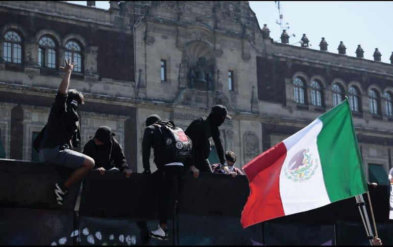 Manifestantes trepan por una valla en inmediaciones del Palacio Nacional en Ciudad de México (CDMX). EFE/J. Méndez