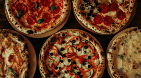 La pizza es un plato italiano, originario de Nápoles; es una base de masa de pan horneada cubierta tradicionalmente con salsa de tomate queso mozzarella y otros ingredientes. CANVA