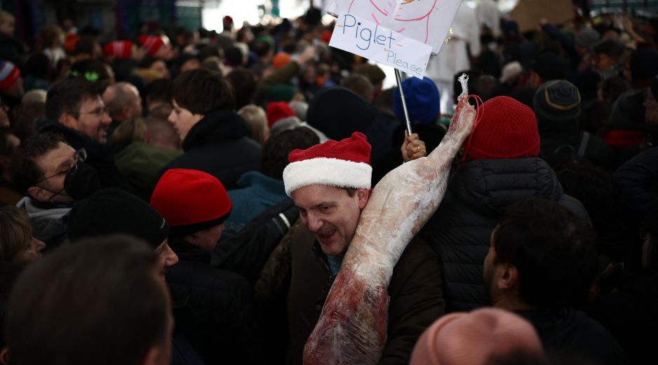 Un cliente se marcha con su compra durante la tradicional subasta de Nochebuena en el mercado de carne de Smithfield, en Londres. AFP / H. Nicholls