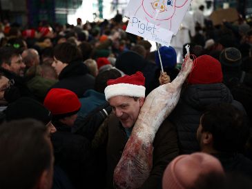 Un cliente se marcha con su compra durante la tradicional subasta de Nochebuena en el mercado de carne de Smithfield, en Londres. AFP / H. Nicholls