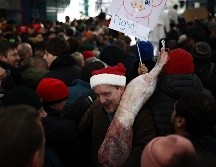 Un cliente se marcha con su compra durante la tradicional subasta de Nochebuena en el mercado de carne de Smithfield, en Londres. AFP / H. Nicholls