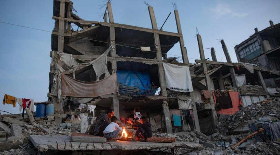 Desplazados palestinos junto a un fuego en los restos de un edificio en Kah Yunis. EFE / EPA / HAITHAM IMAD