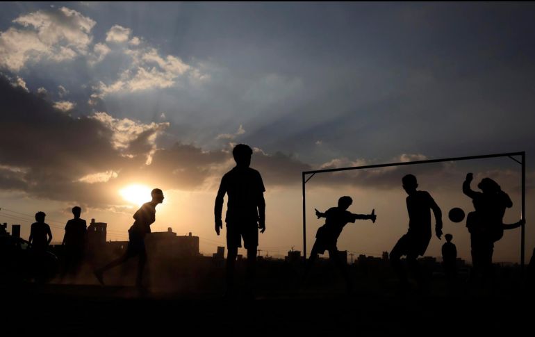 Personas, bajo el sol poniente, mientras juegan futbol en la víspera de Año Nuevo en Sana'a, Yemen. EFE / Y. Arhab