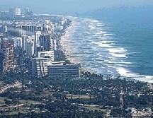 Vista panorámica de una playa en México, donde turistas disfrutan del sol y el mar, reflejando el atractivo natural del país. SUN