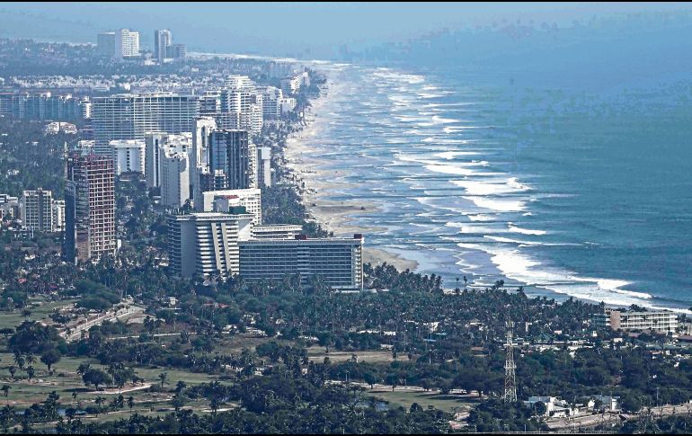 Vista panorámica de una playa en México, donde turistas disfrutan del sol y el mar, reflejando el atractivo natural del país. SUN