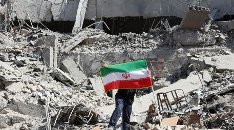 Un iraní coloca la bandera nacional de Irán entre las ruinas de una comisaría de policía dañada en el centro de Teherán, Irán, este miércoles. EFE/ A. Taherkenareh