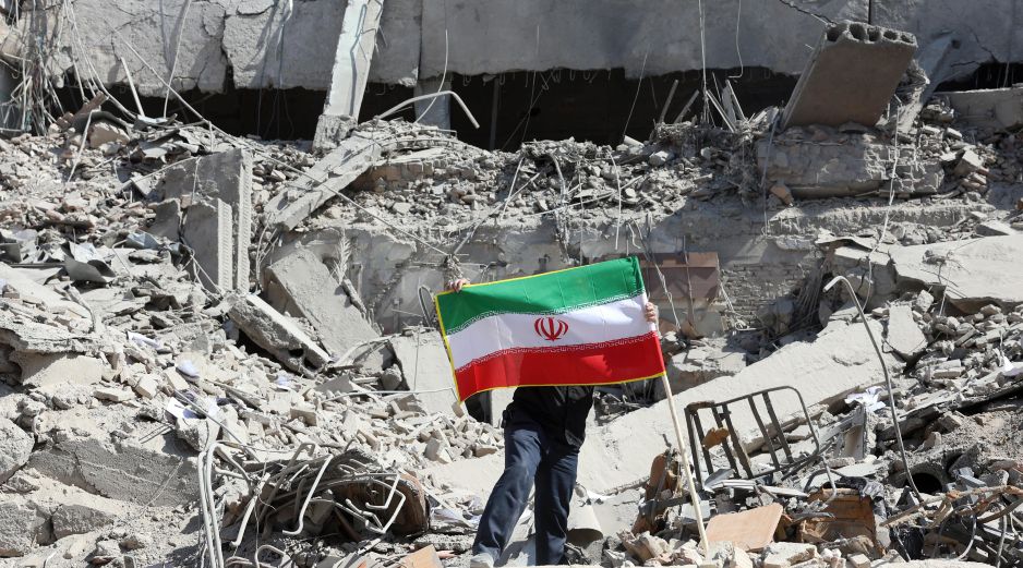 Un iraní coloca la bandera nacional de Irán entre las ruinas de una comisaría de policía dañada en el centro de Teherán, Irán, este miércoles. EFE/ A. Taherkenareh