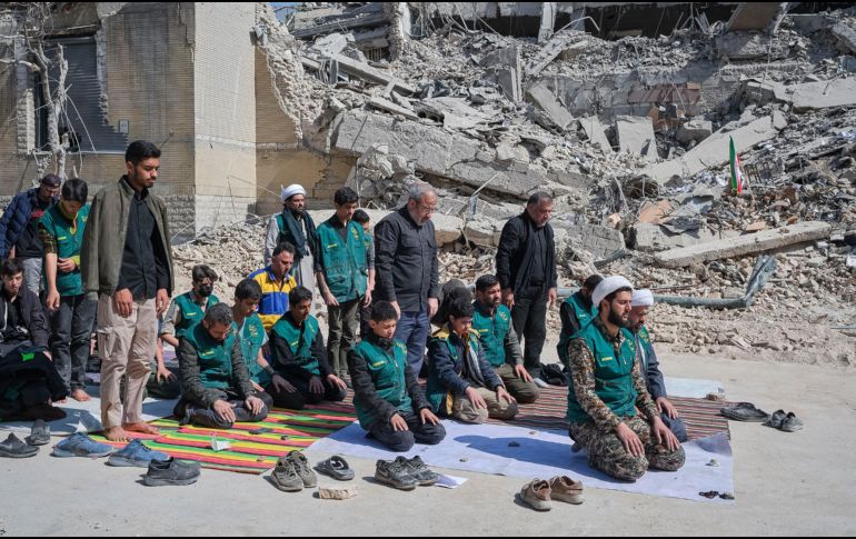 Un grupo de voluntarios basijis -milicia islámica- reza este miércoles, al lado de un edificio destruido en los bombardeos israelíes-estadounidenses contra Irán en la calle en la calle Kargar, cerca de la plaza Engelab en Teherán. EFE/ J. León