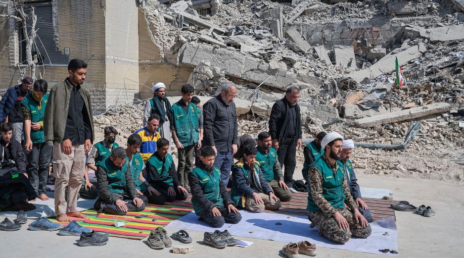 Un grupo de voluntarios basijis -milicia islámica- reza este miércoles, al lado de un edificio destruido en los bombardeos israelíes-estadounidenses contra Irán en la calle en la calle Kargar, cerca de la plaza Engelab en Teherán. EFE/ J. León
