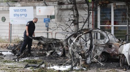 Un policía israelí inspecciona coches calcinados tras el impacto de fragmentos de un misil balístico iraní interceptado en Tel Aviv, Israel, el 15 de marzo de 2026. EFE/A. SULTAN