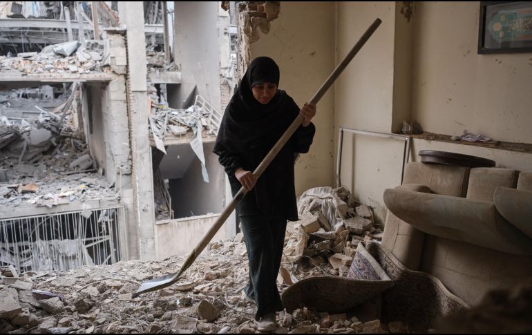 Una mujer trata de limpiar una vivienda en el barrio de Haft Chenar de Teherán que resultó dañada en un ataque de Estados Unidos e Israel. EFE/J. León