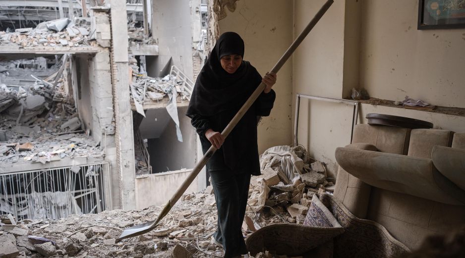 Una mujer trata de limpiar una vivienda en el barrio de Haft Chenar de Teherán que resultó dañada en un ataque de Estados Unidos e Israel. EFE/J. León