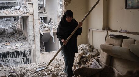 Una mujer trata de limpiar una vivienda en el barrio de Haft Chenar de Teherán que resultó dañada en un ataque de Estados Unidos e Israel. EFE/J. León