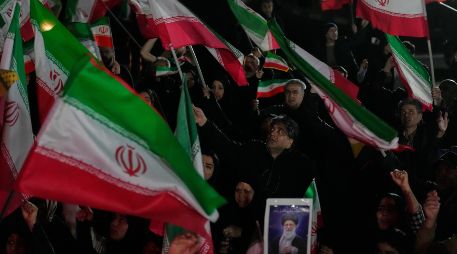Partidarios del gobierno ondean banderas iraníes durante una manifestación en una plaza. AP/V. Salemi