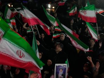 Partidarios del gobierno ondean banderas iraníes durante una manifestación en una plaza. AP/V. Salemi