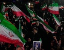 Partidarios del gobierno ondean banderas iraníes durante una manifestación en una plaza. AP/V. Salemi
