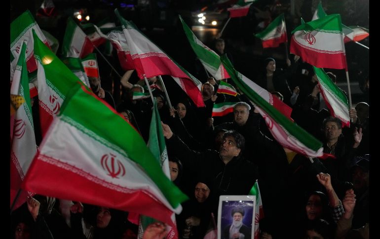 Partidarios del gobierno ondean banderas iraníes durante una manifestación en una plaza. AP/V. Salemi