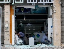 Trabajadores limpian los cristales rotos de una farmacia tras un ataque israelí en la zona de Al Chiyah, un suburbio al sur de Beirut, Líbano. EFE/W. Hamzeh