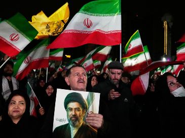 Iraníes ondean banderas durante un acto en apoyo a su gobierno en una plaza en el oeste de Teherán. AP/V. Salemi