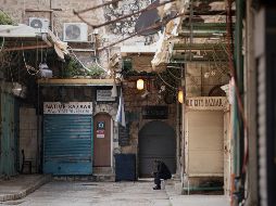 Un hombre se sienta junto a una puerta de la iglesia del Santo Sepulcro que permanece cerrada. AP/M. Illean