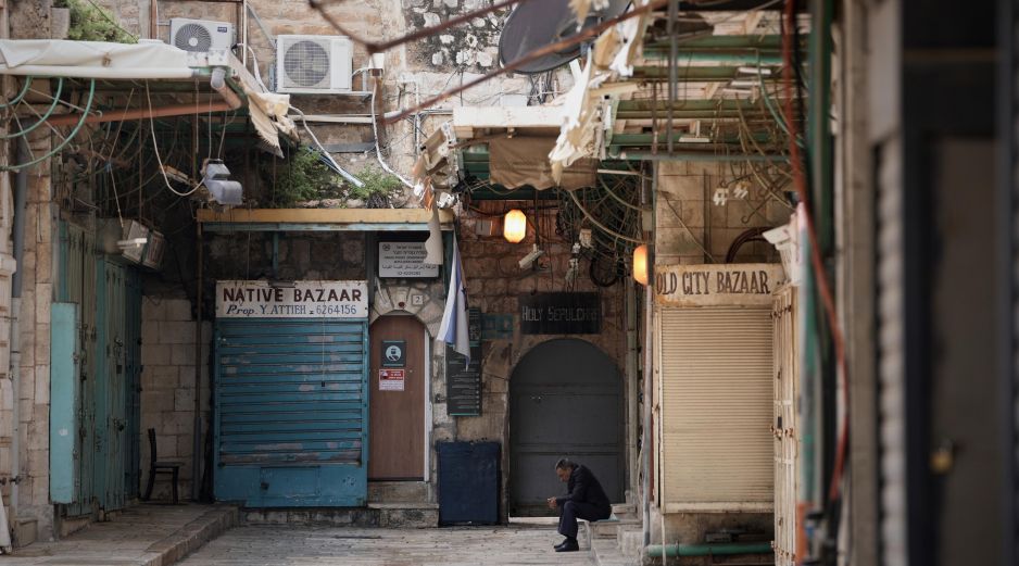 Un hombre se sienta junto a una puerta de la iglesia del Santo Sepulcro que permanece cerrada. AP/M. Illean