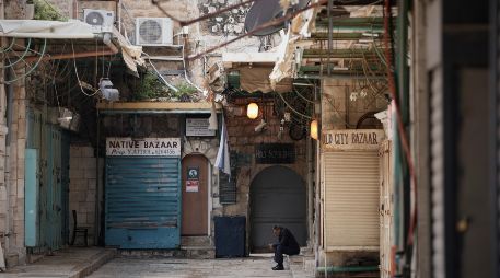 Un hombre se sienta junto a una puerta de la iglesia del Santo Sepulcro que permanece cerrada. AP/M. Illean