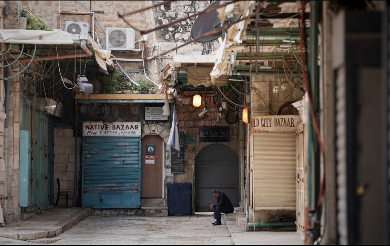 Un hombre se sienta junto a una puerta de la iglesia del Santo Sepulcro que permanece cerrada. AP/M. Illean