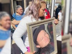 Ceci Flores sostiene una foto de tu hijo durante la misa de este jueves. SUN/ESPECIAL