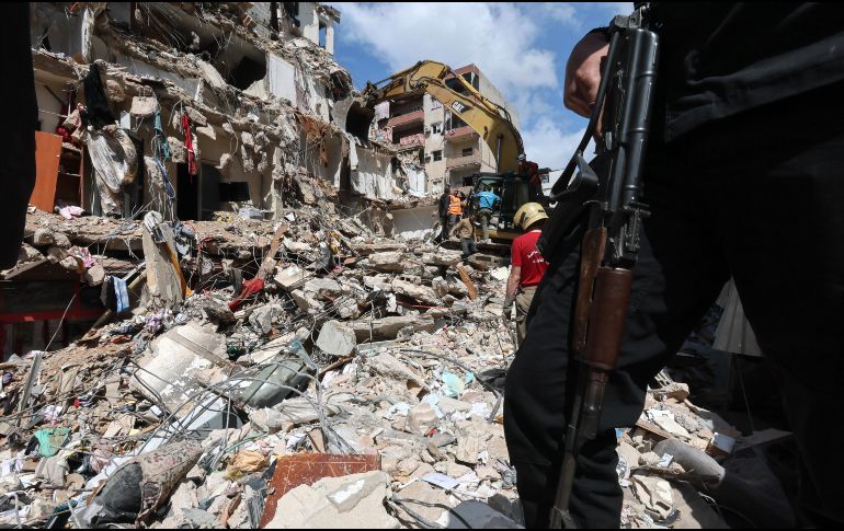Un hombre armado monta guardia mientras una excavadora retira los escombros de un edificio parcialmente destruido tras un ataque aéreo israelí, durante una visita de prensa organizada por la oficina de prensa de Hezbolá, en Líbano. EFE/W. HAMZEH