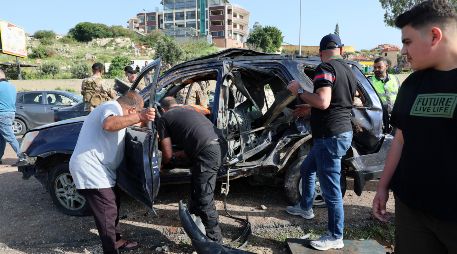 Varias personas trabajan en el lugar de un ataque aéreo israelí que impactó un vehículo en la ciudad de Jiyeh, al sur de Beirut, Líbano. EFE/W. Hamzeh