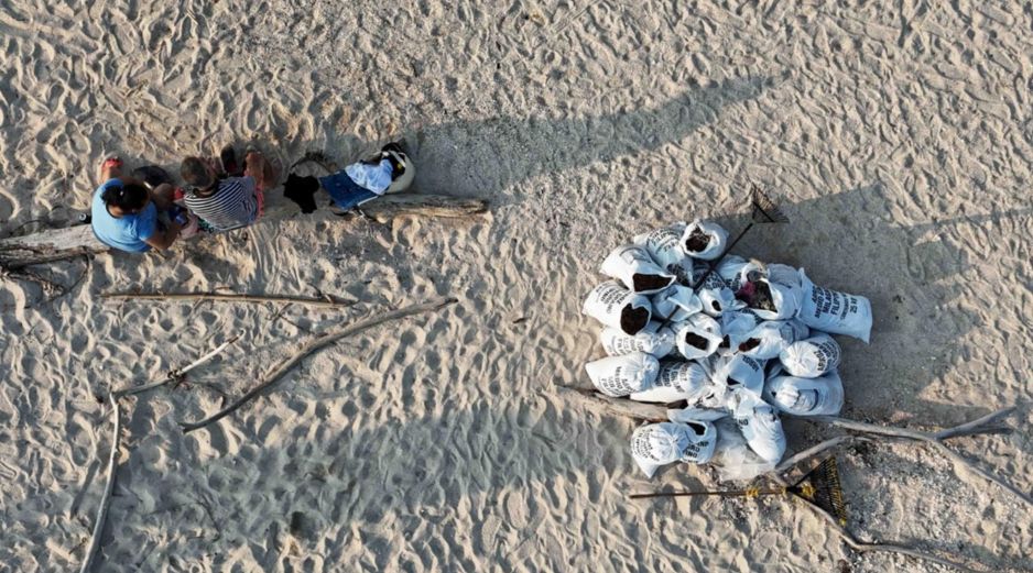 Trabajadores descansan después de llenar costales con arena contaminada con petróleo. El derrame reportado desde inicios de febrero de 2026, y que todavía sigue dejando estragos, se originó por una fuga detectada en uno de los ductos del complejo Cantarell. SUN/D. Prado