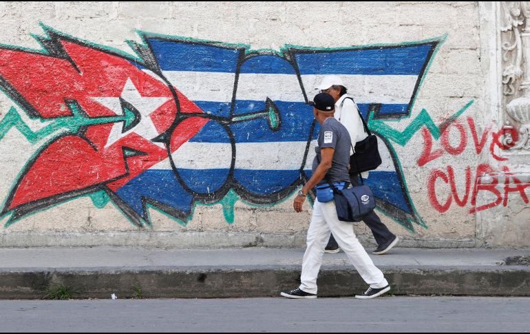 Personas caminan frente a un mural con la bandera de Cuba en La Habana. EFE/E. Mastrascusa