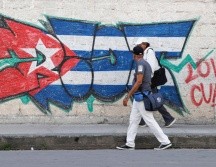 Personas caminan frente a un mural con la bandera de Cuba en La Habana. EFE/E. Mastrascusa