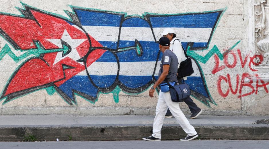Personas caminan frente a un mural con la bandera de Cuba en La Habana. EFE/E. Mastrascusa