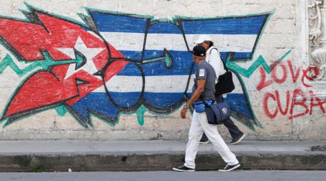 Personas caminan frente a un mural con la bandera de Cuba en La Habana. EFE/E. Mastrascusa