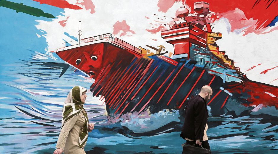 Habitantes de la capital persa caminan junto a un mural donde se exalta la fortaleza militar de su nación frente a la armada estadounidense. EFE