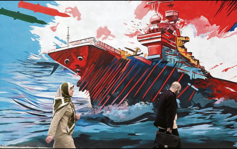 Habitantes de la capital persa caminan junto a un mural donde se exalta la fortaleza militar de su nación frente a la armada estadounidense. EFE