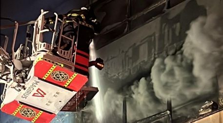 Bomberos utilizan una escalera telescópica para atacar el incendio en uno de los edificios afectados. X/JefeVulcanoCova