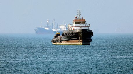Remolcador iraní navega cerca de un buque anclado en el Estrecho de Ormuz, frente a Bandar Abbas; Teherán niega paso de barcos comerciales. AFP